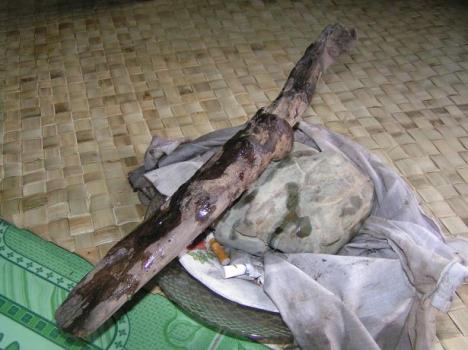 Two artifacts stored in one of the houses. The wooden staff is similar in shape to a knife, this was thought to be very unusual. The stone according to the story was a turtle in the stream, only when a spear was thrown at it it turned into a stone. Both artifacts are thought to be powerfull and both are offered rice wine, cigarettes and money. 